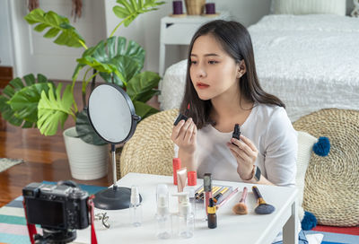 Young woman applying make-up at home