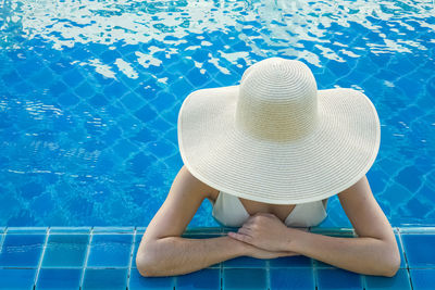 Midsection of woman wearing hat in swimming pool