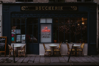 Chairs and tables at sidewalk cafe in city