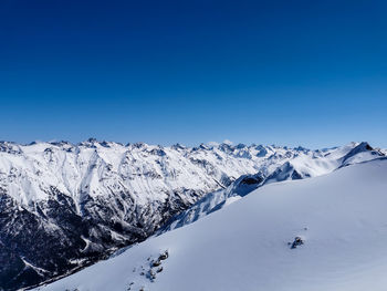 Scenic view of snowcapped mountains against clear blue sky