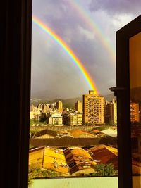 Rainbow over city against sky