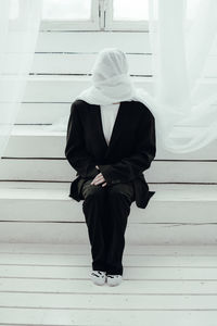 Rear view of woman standing against white wall