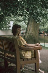 Full length of woman sitting on bench in park