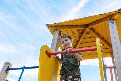 Cute caucasian boy on playground on summer day. blue sky on background