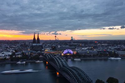 View of cityscape against river during sunset