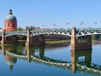 Reflection of bridge over river against clear sky