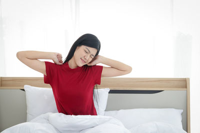 Young woman sitting on bed at home