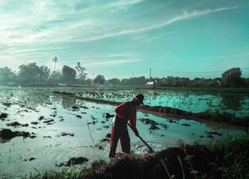 Man standing by lake against sky
