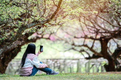 Full length of woman sitting on mobile phone