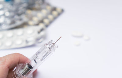 Cropped hand of man holding syringe on table