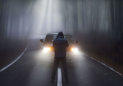 Rear view of man standing on illuminated light trail