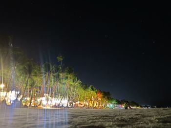 Illuminated beach against sky at night