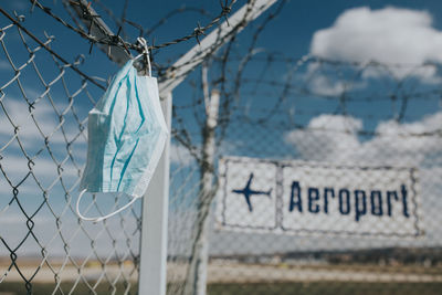 Close-up of text on fence against sky