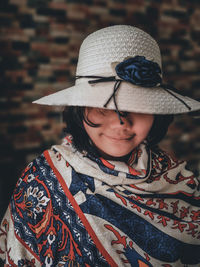 A young girl wearing a patterned scarf and a hat obscuring her face 