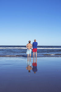 Friends on beach against clear sky