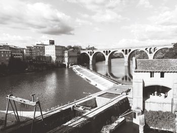 Bridge over river in city against sky