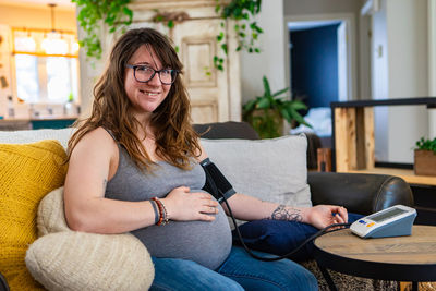 Portrait of smiling woman sitting on sofa at home