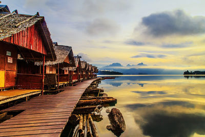 Scenic view of lake by buildings against sky during sunset