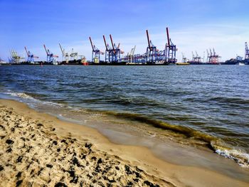 Cranes at commercial dock against sky