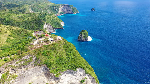 Blue sea washes rocky mountains covered forest. separate rocks in water. nusa penida indonesia