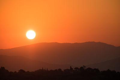 Scenic view of silhouette mountains against orange sky