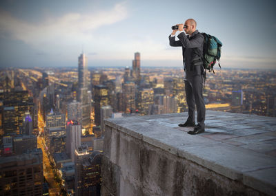 Man standing by modern buildings against sky in city