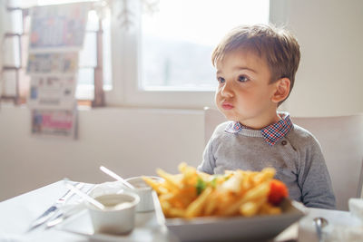 Cute boy sitting at dining table at home