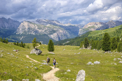 Rear view of hikers walking on trail against mountains