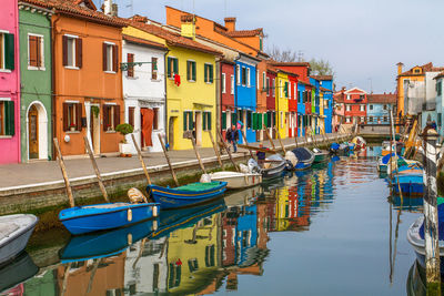 Boats moored in canal by buildings in city