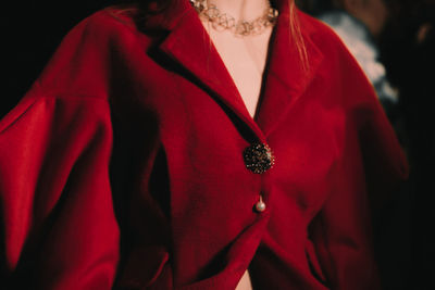 Part of a female body dressed in an elegant red jacket with golden buttons. women's  accessories