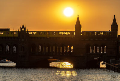 Arch bridge over river during sunset