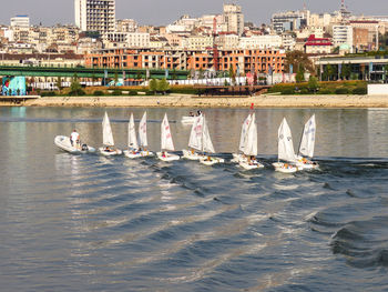 Sailboats moored on sea against buildings in city