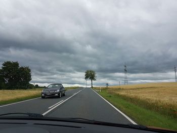 Country road against cloudy sky