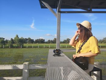 Woman standing by railing against sky