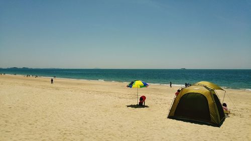 Tent at beach against clear sky on sunny day