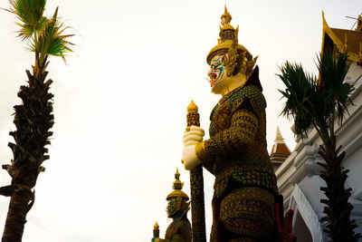 Low angle view of statue against temple building against sky