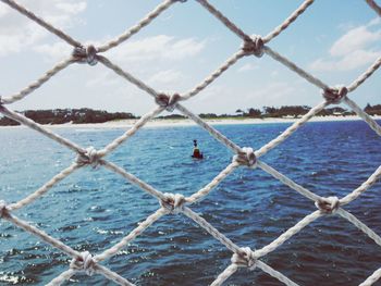 Sea against sky seen through fence