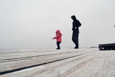 Man with baby girl on floorboard against clear sky