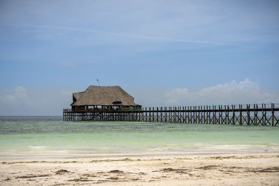 Built structure on beach by sea against sky