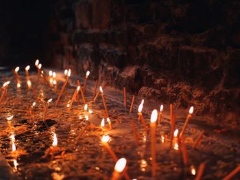 Close-up of lit candles in temple at night