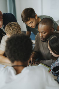 Male teacher discussing with high school students in classroom