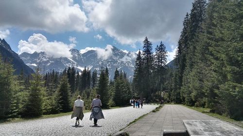 People walking on mountain road against sky