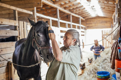 Side view of senior woman standing in stable