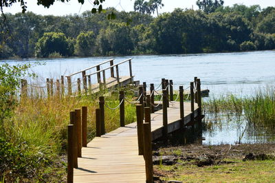 Wooden posts on footpath by lake