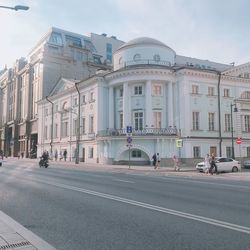 Road by buildings against sky