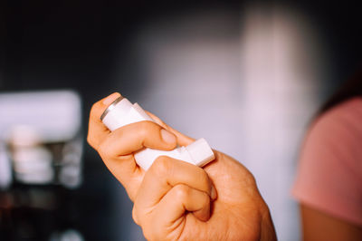 Cropped hand of woman holding asthma inhaler