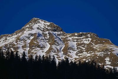 Low angle view of snowcapped mountain against blue sky