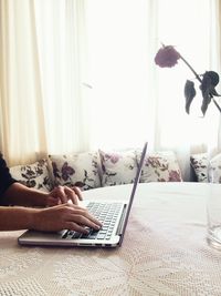 Close-up of hand using laptop on bed at home