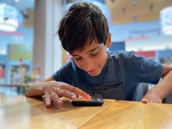 Side view of boy using mobile phone at home