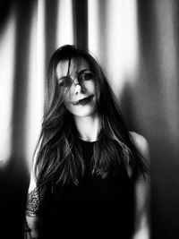 Portrait of young woman standing against wall